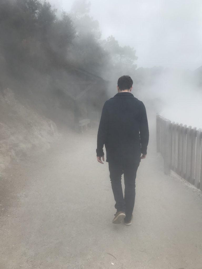 man walking through sulfur clouds