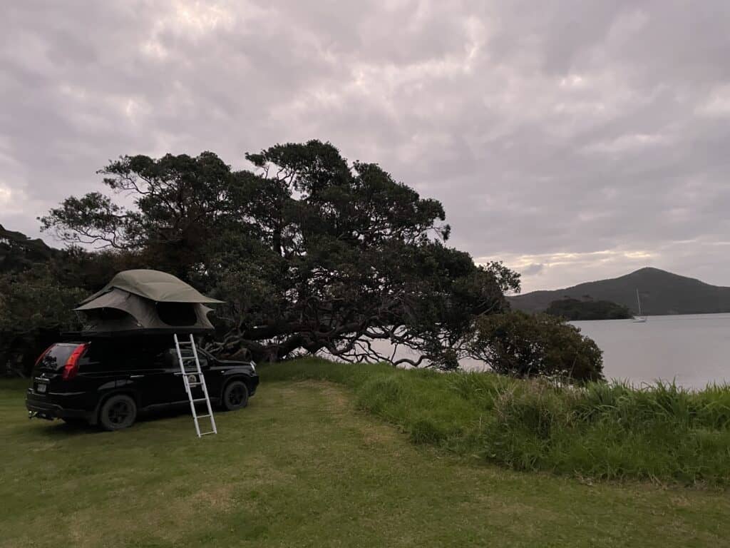 Rooftop tent camping next to a bay