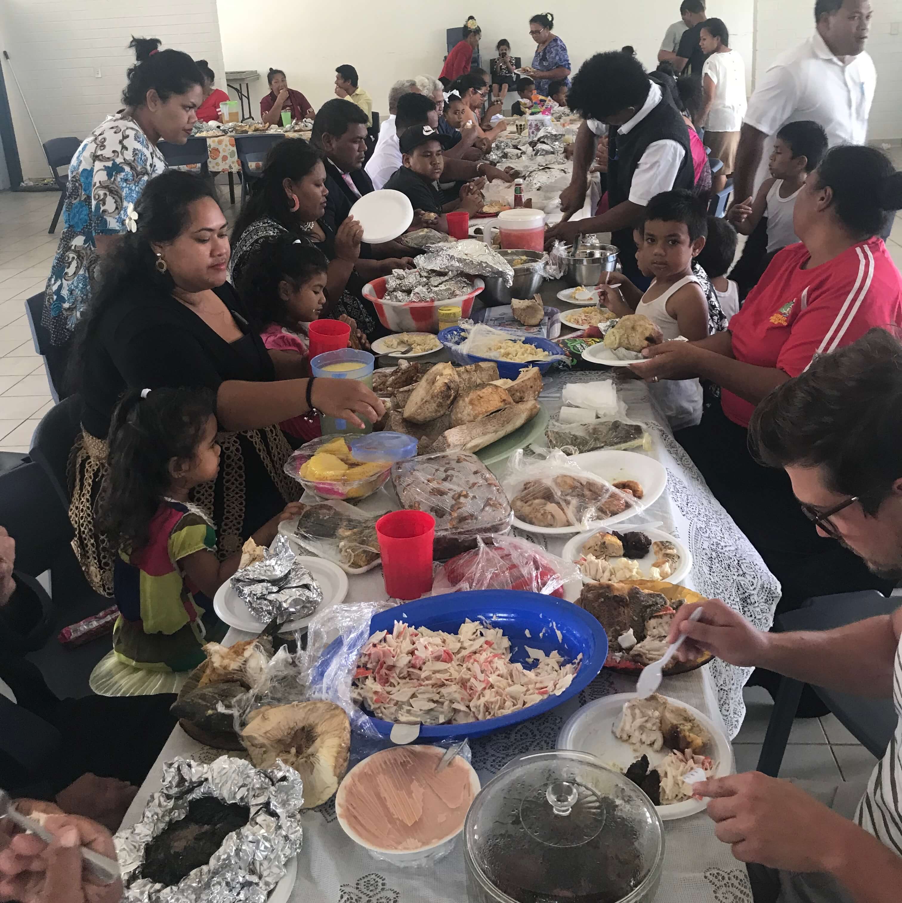 Large dining table full of food and surrounded by people