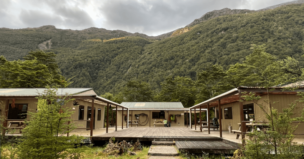 Basic wooden hut at the foot of the mountains in Milford Sound