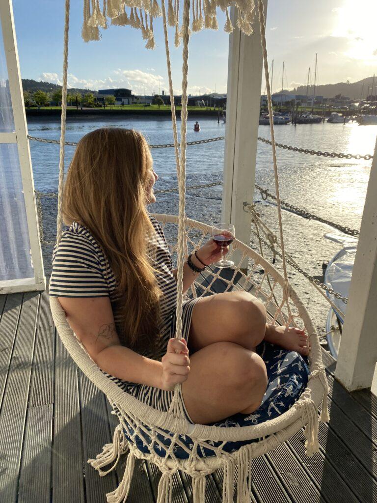 Girl sipping wine in a hanging chair overlooking Whanagarei harbour