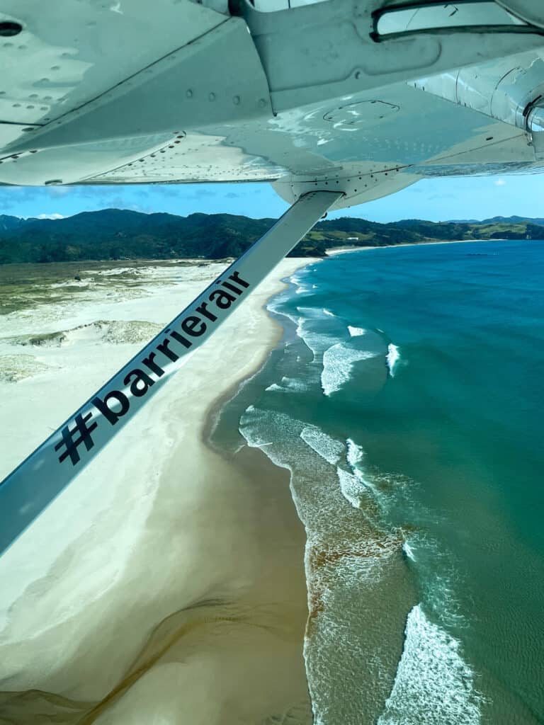 Plane landing near a long beach on Great Barrier Island