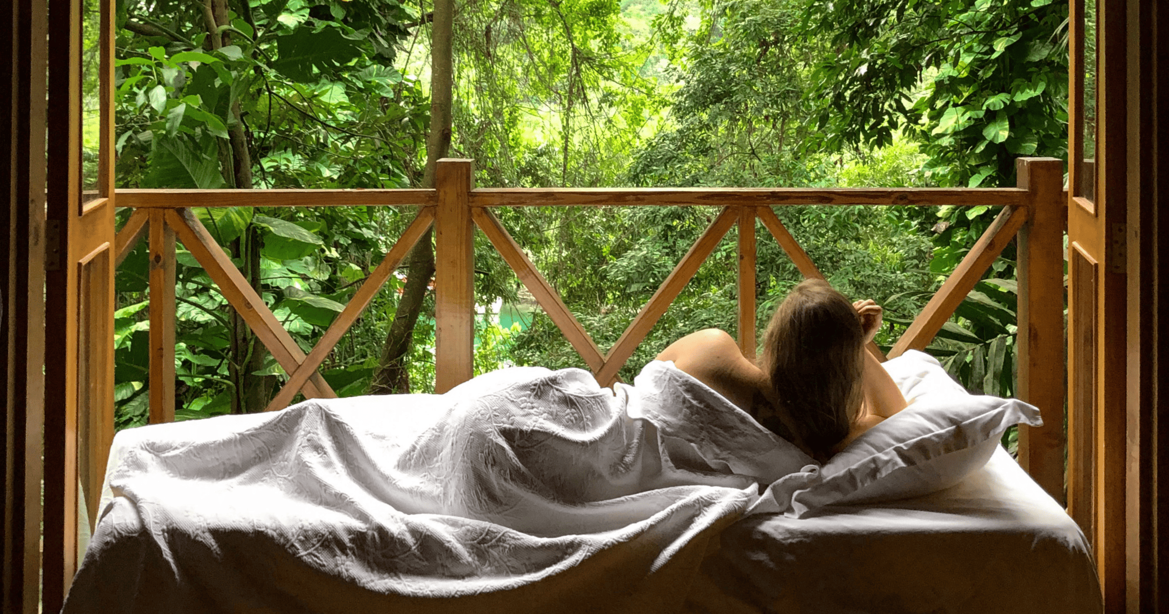 Woman in Bed Overlooking the Jungle in Jamaica