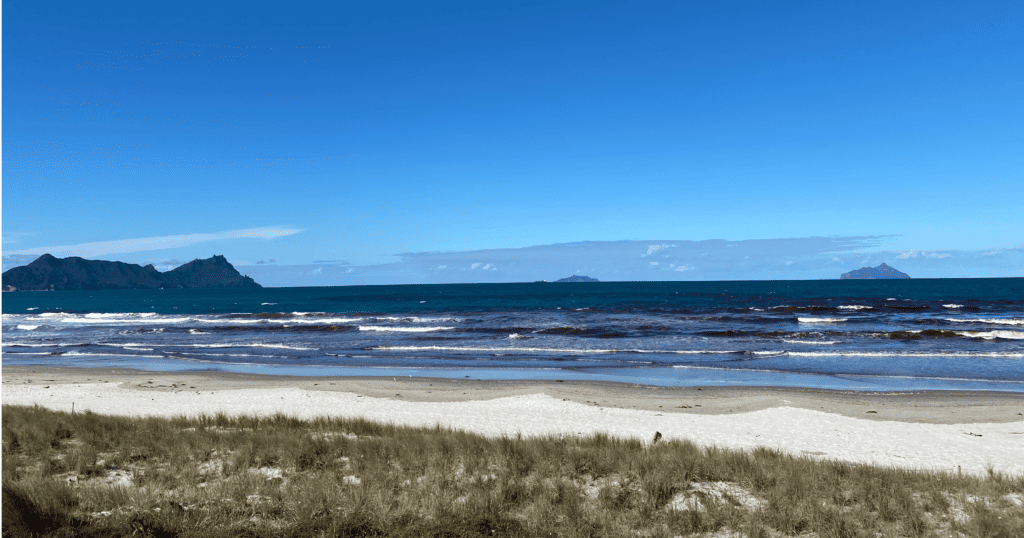 Long beach with white sand with Brynderwyn Hills