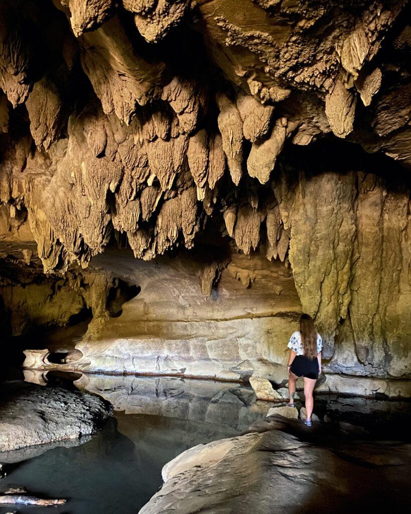 Girl standing inside a cave with stalactite ceiling