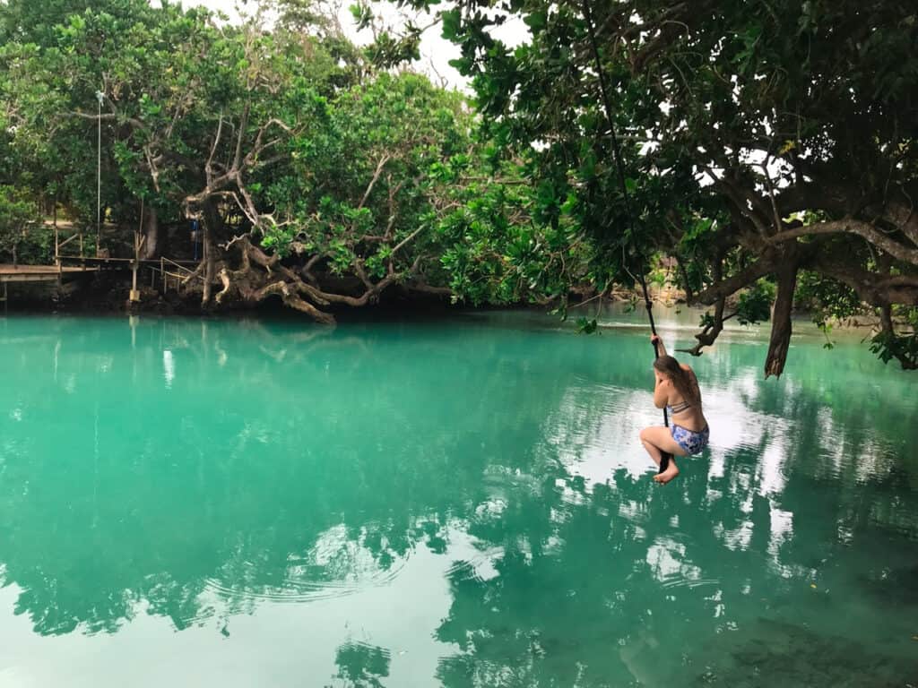 Girl rope swinging into the Blue Lagoon Port Vila Vanuatu