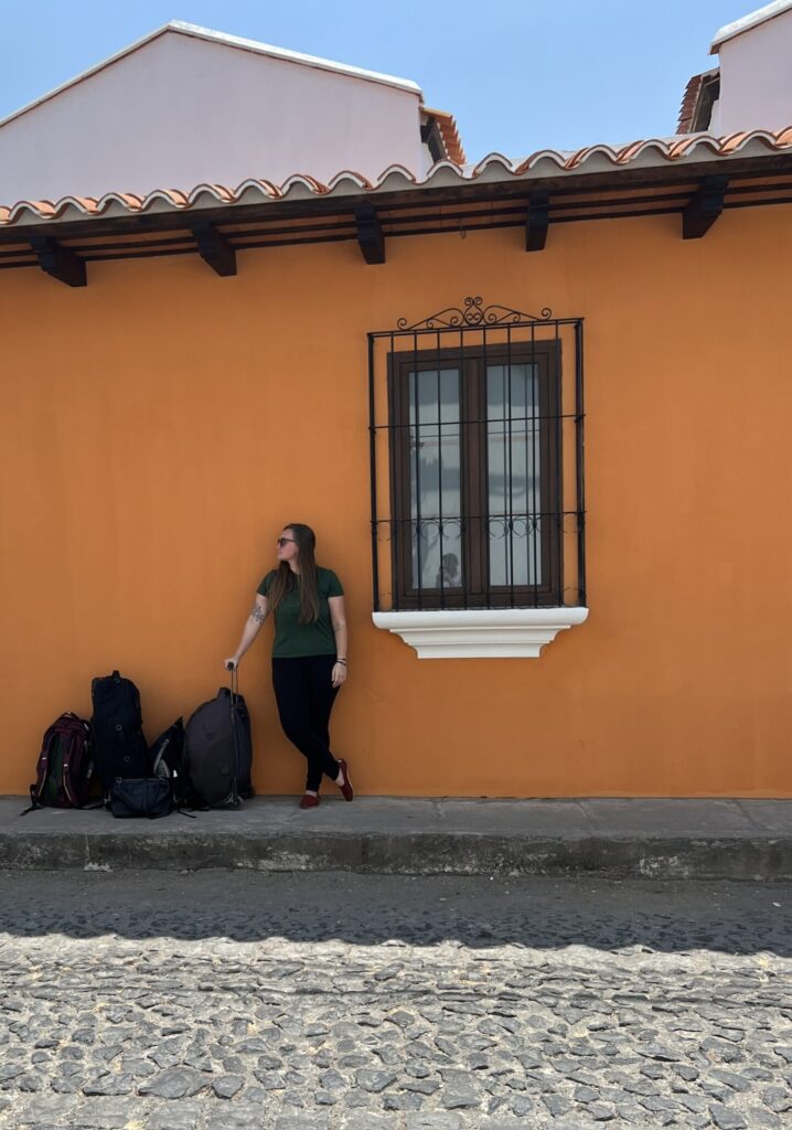 Orange wall in Antigua, girl with suitcases