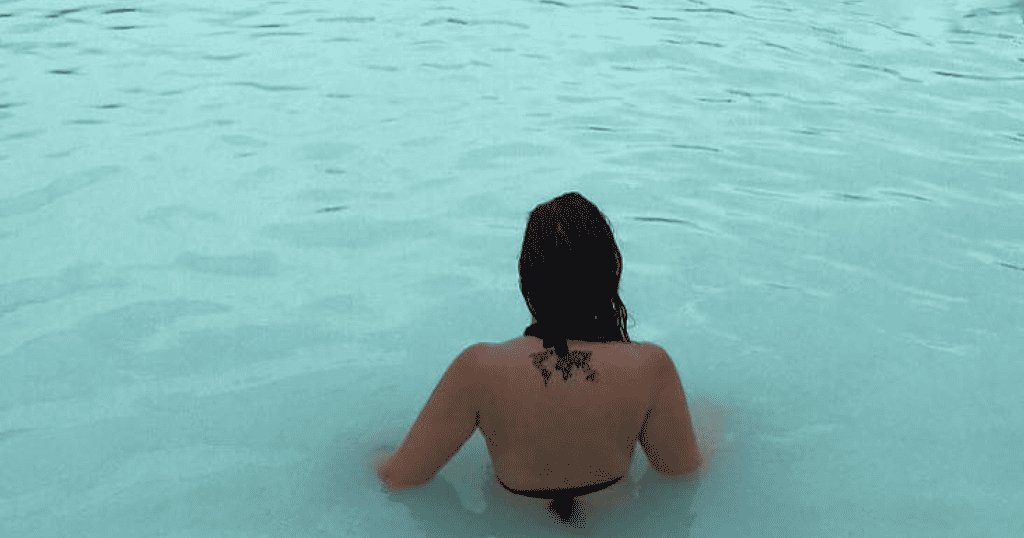 Girl standing in opaque blue water at a hot spring in Iceland, the Blue Lagoon