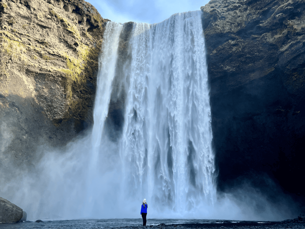 Girl standing at the base of the most famous Iceland Waterfall, Skogafoss