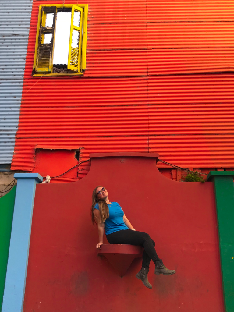 Girl sitting on colourful wall