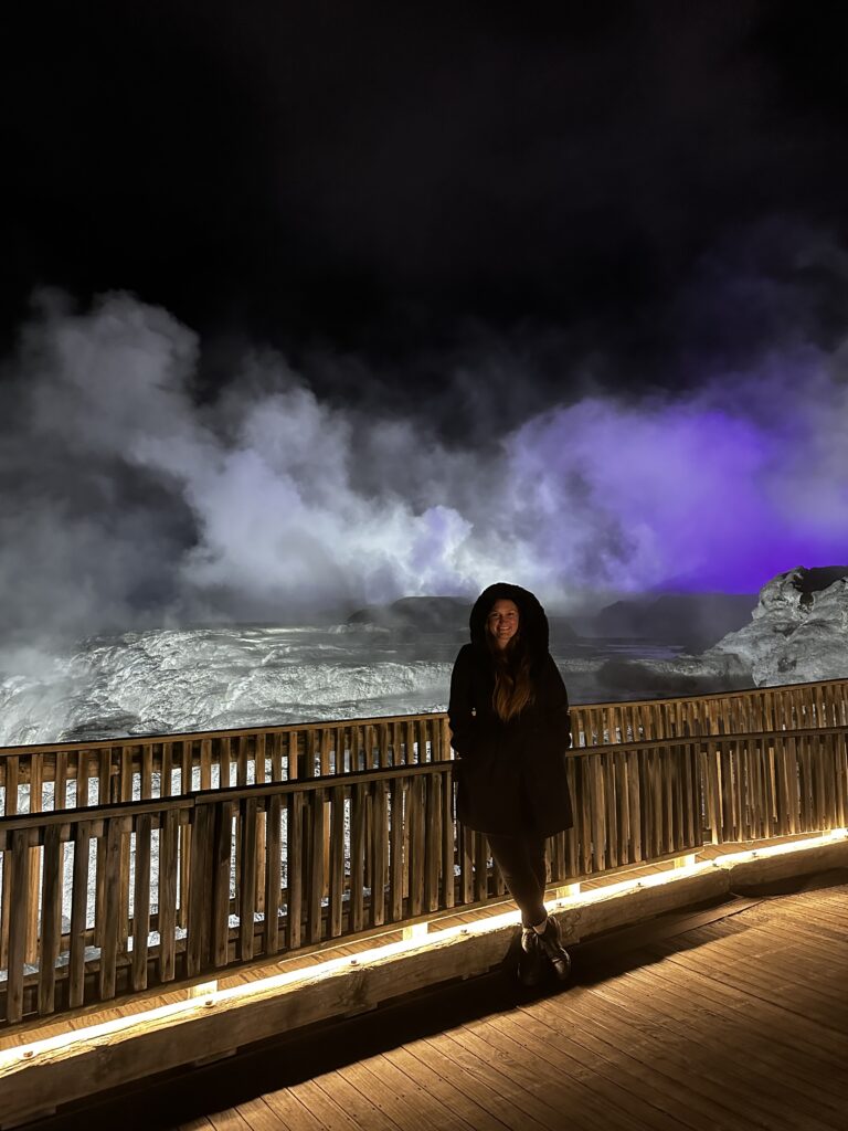 Girl in front of geyser at night in Rotorua