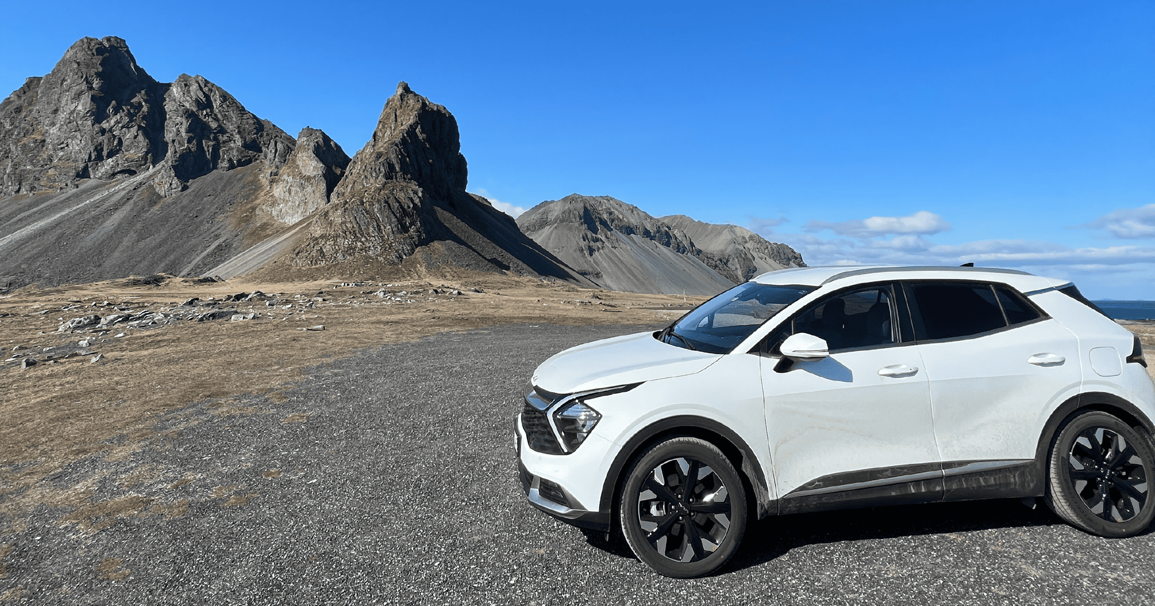 White car in front of mountains in Iceland, one of the most beautiful road trips in the world