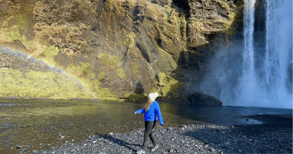 Girl between rainbow and waterfall