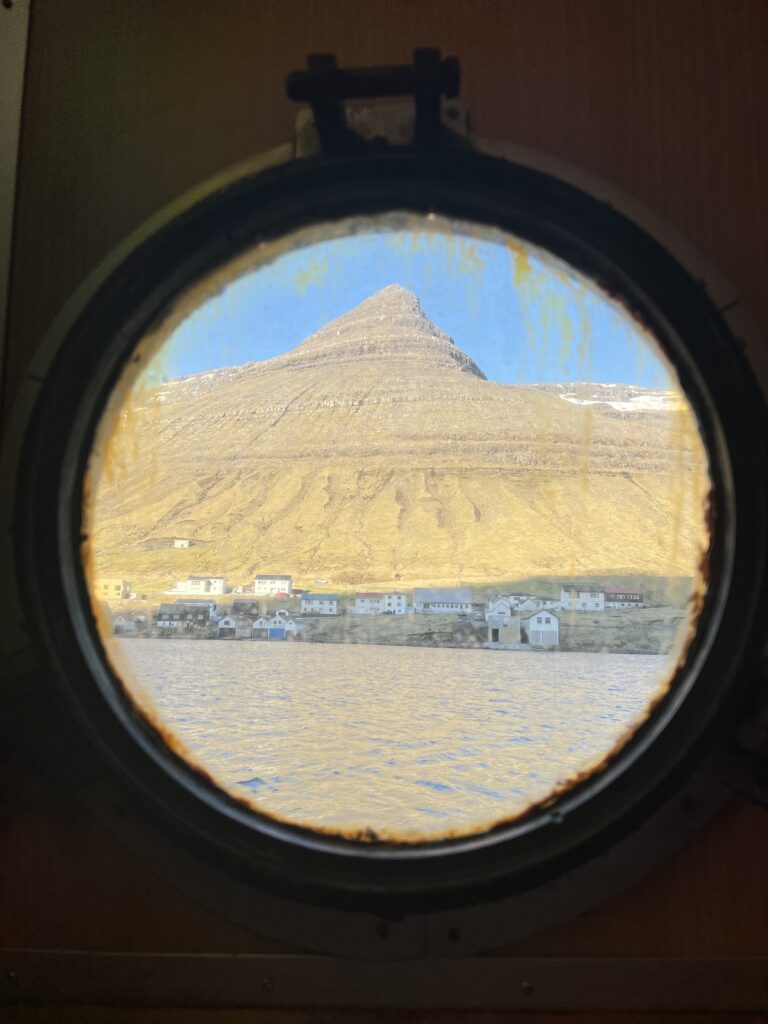 Mountain through round, dirty ship window