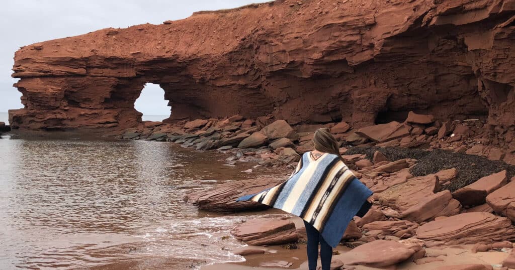 Girl standing on red beach on a Canadian road trip