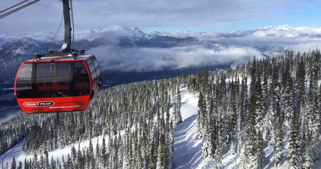 Red gondola car ascending snowy mountain in Whistler, BC