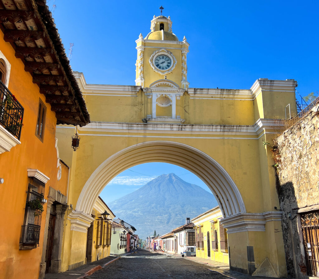 Antigua yellow arch with active volcano in the distance