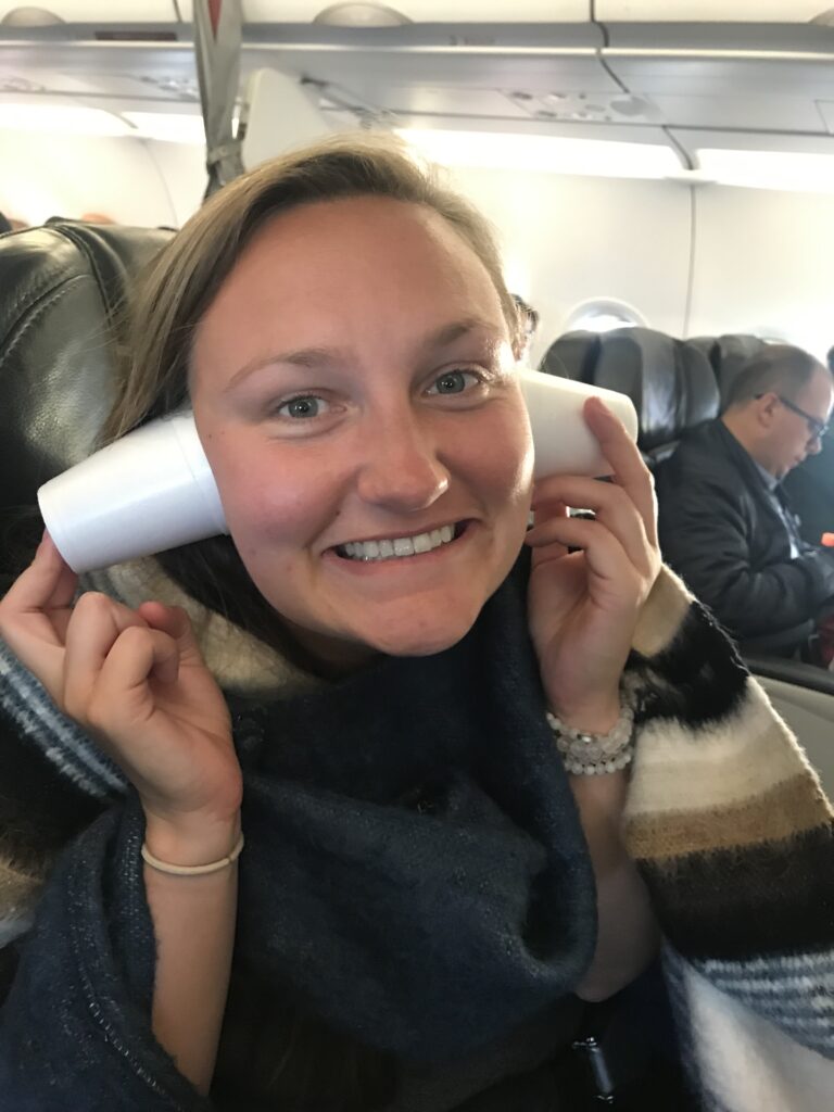 girl with styrofoam cups covering her ears on a plane