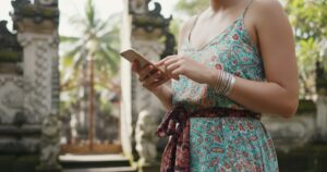 woman texting outside a bali Temple using the best eSIM for Indonesia
