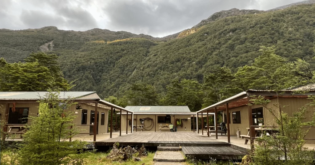 Basic wooden hut at the foot of the mountains in Milford Sound