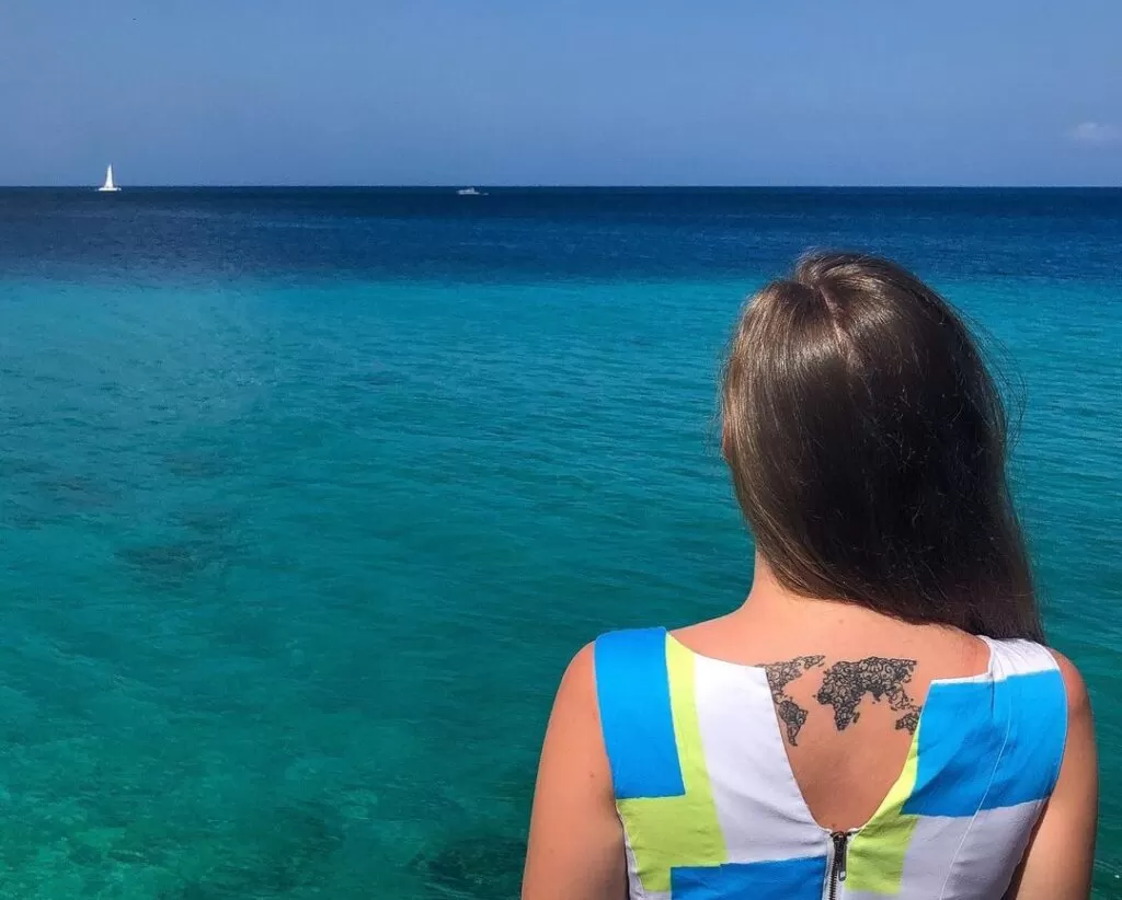 Me looking out at the ocean in Jamaica with world map tattoo on my back