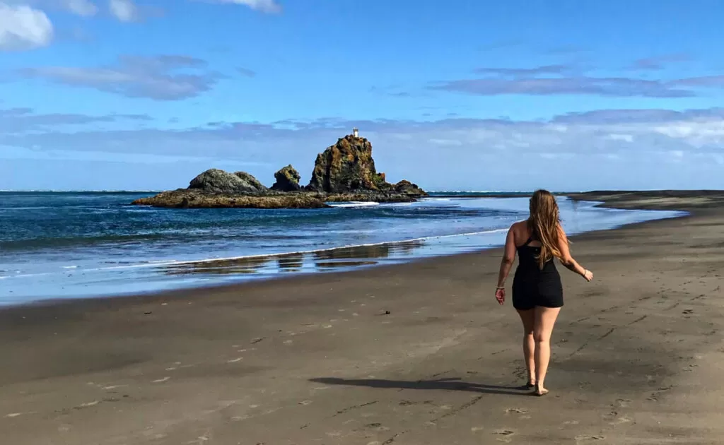 Girl walking on Whatipu beach near the glow worm caves in Auckland